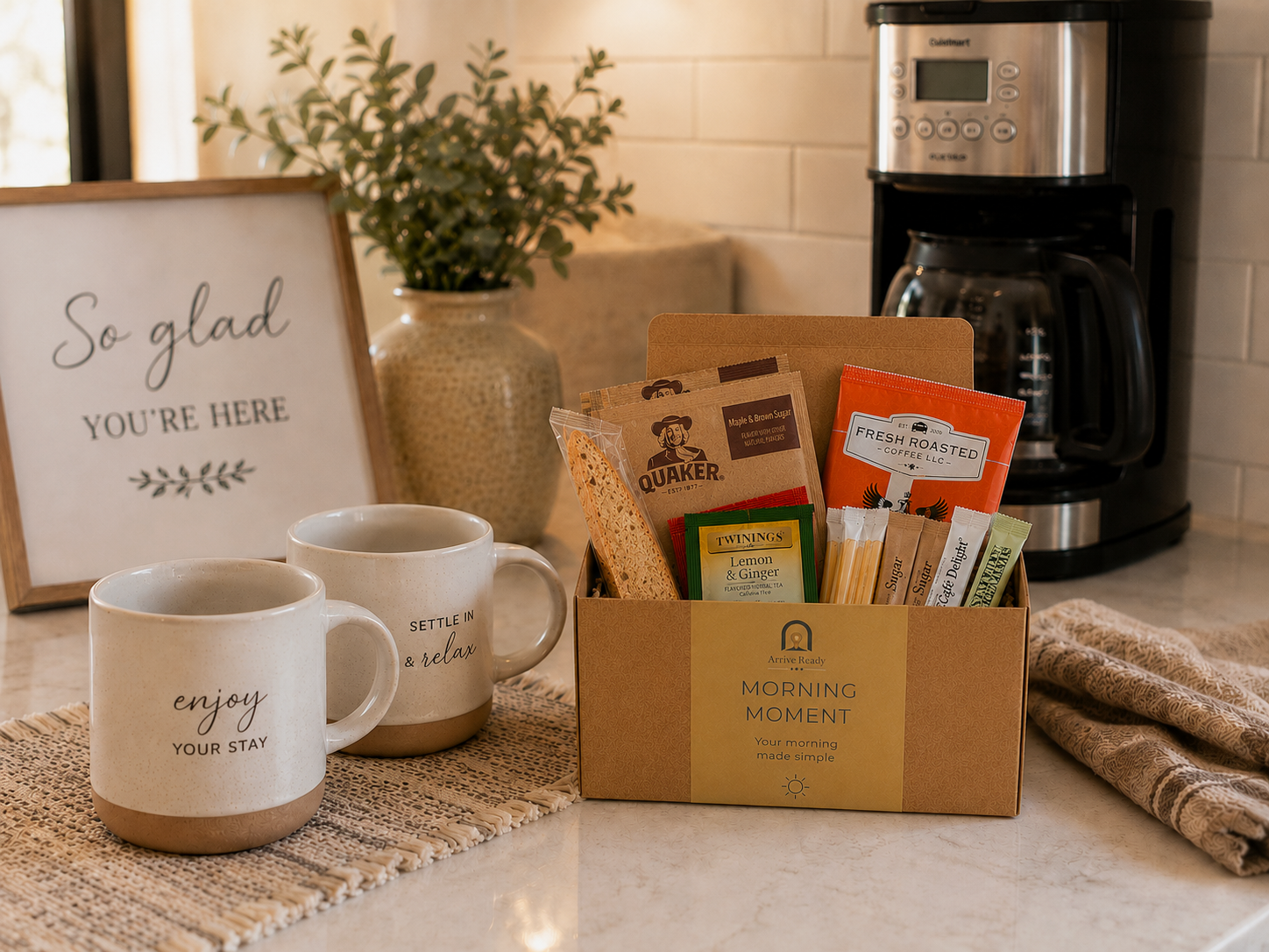 Arrive Ready Morning Moment Arrival Kit on the counter in a vacation rental welcoming guests with coffee maker in the background and cups for breakfast. kraft gift box contains coffee, sugar, tea